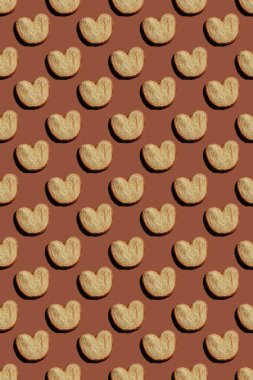 seamless pattern palmier cookies on brown background. vector illustration