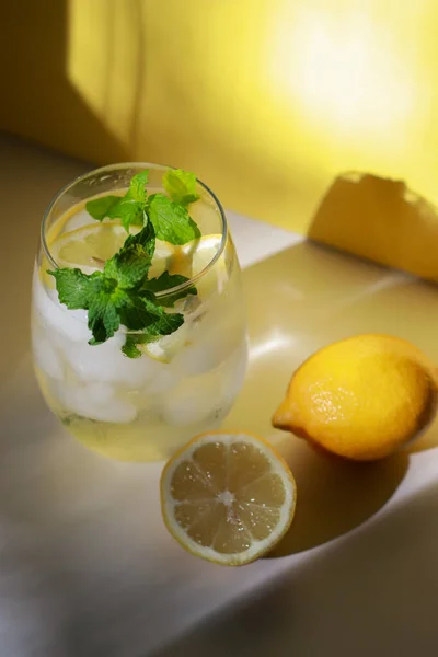 Ποτήρι Νερό Μέντα Λεμόνι Και Πάγο Λευκό Τραπέζι Κίτρινο Φόντο — Φωτογραφία Αρχείου