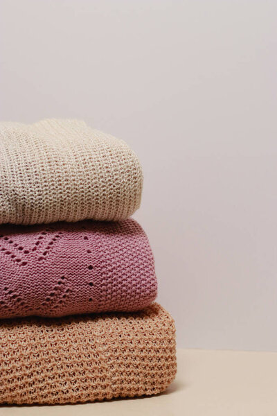 stack of folded knitwear, minimal lifestyle, capsule wardrobe, copy space