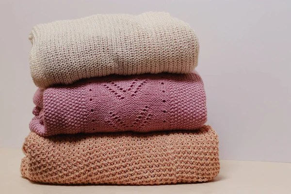 stack of folded knitwear, minimal lifestyle, capsule wardrobe, copy space