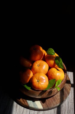 Mandalinaları ahşap bir kasede yapraklarla kapatın.