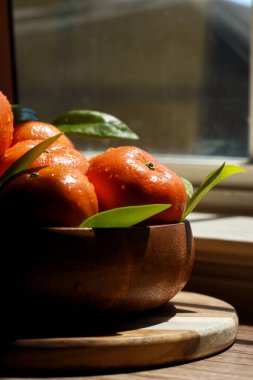 Ahşap bir kasede yapraklarla Mandarin 'lerin etrafını sarın. Yüksek kalite fotoğraf