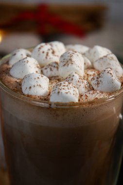 Camdan bir fincanda sıcak çikolatanın üzerinde mini şekerlemeler, bulanık ışık arka planında. Yüksek kalite fotoğraf