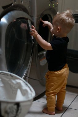 Çamaşır makinesinin düğmeleriyle oynayan bir çocuk. Yüksek kalite fotoğraf