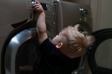 Çamaşır makinesinin düğmeleriyle oynayan bir çocuk. Yüksek kalite fotoğraf