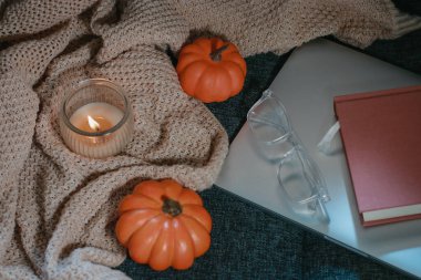 Arka planda kal. Küçük balkabakları, kurusıkı örgü, kanepede defter ve gözlük.. 