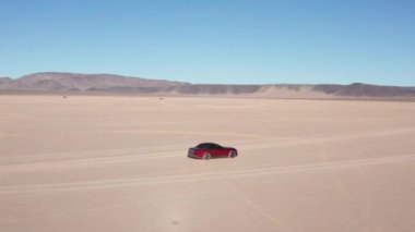 Çölde uçan bir spor arabanın 4K görüntüsü.