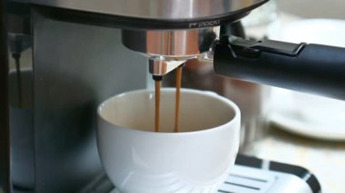 Kahve makinesi seramik bardağa bir fincan lezzetli köpüklü aromalı kahve koyuyor.