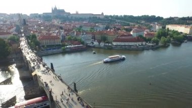 Aerial view of Vltava River with two boats floating under the Charles Bridge.