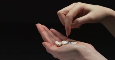 Woman choosing a pill from her hand.