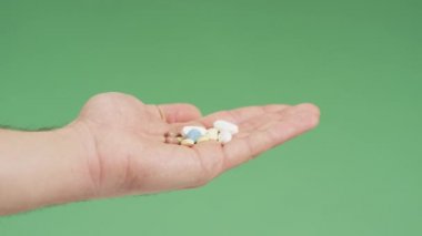 Taking a blue pill from a hand with various meds.