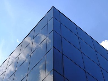 Modern glass building against the blue sky. Bottom view of modern skyscraper in business district