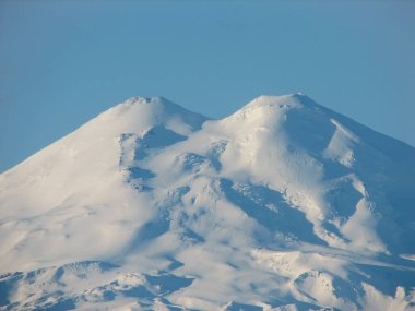 Elbrus is a high mountain. Dormant volcano. mountain covered with snow on blue sky background. Caucasus mountains, slopes