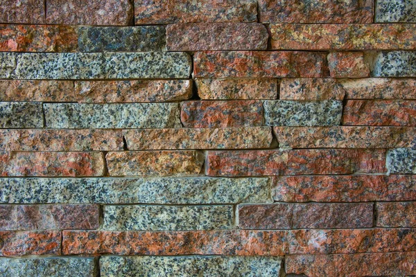 Decorative stone granite of different colors. Background. Blocks and plates of stone on the wall