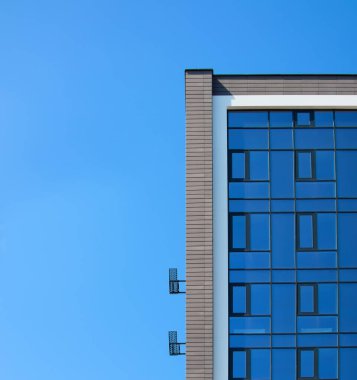 New tall modern building for office or residential apartments against the blue sky. There is free space for text