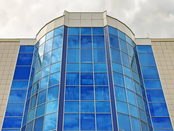 The facade of the building with blue mirror glass on the windows. Modern tall office building