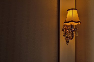 Orange lamp in a vintage wall sconce in the apartment. Warm home light in the bedroom. Place for text