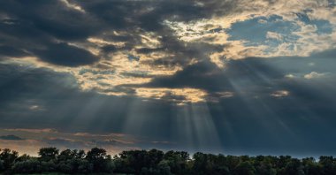 Ormanın üzerindeki bulutlardan gelen güneş ışınları. Bulutlu hava ve güzel doğal manzara