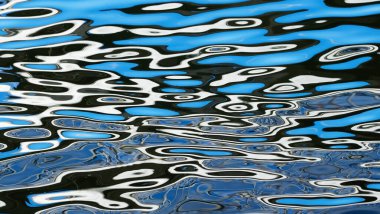 Eğimli beyaz ve mavi çizgiler suyun yüzeyine yansıyor. Dalgalardaki ışık dalgaları