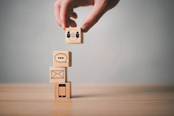 Communication through websites, e-mail and telephone channels To contact the business and chat with customers by hotline The wooden dice are stacked and have communication icons.