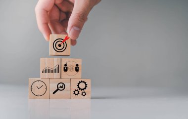 Masa grisinin üzerindeki tahta küpler. El üst taraftaki blokları topluyor. Yaratıcı Zeka yeni şeyler öğreniyor. Yeni yenilikler geliştiriyor. Başarı için hedefler belirliyor..
