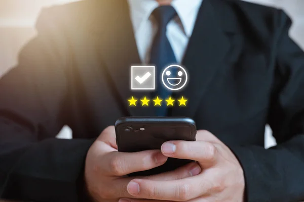 Men use their smartphones to rate customer service and satisfaction. Emoticons, happy smiley faces to provide satisfaction in service and rate of service rating. Buying products online Doing business.