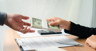 Bir banka çalışanı emlak yatırım kredisi olarak ipotek ve ev sigortası teklifleri için onaylanmış sözleşme başvurusu ile dolar teklif eder. Gelecekteki yatırımlar için borç alma ve kredi oluşturma.