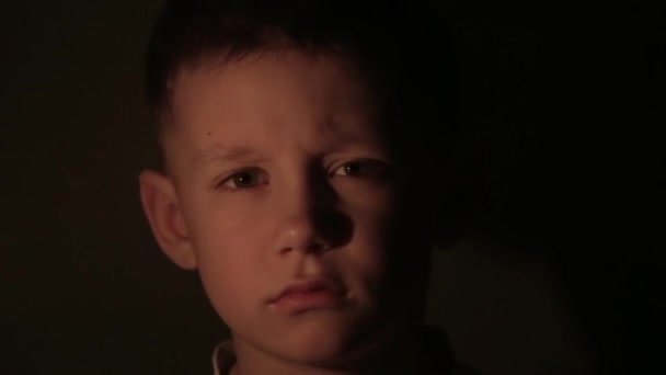Κοντινό πλάνο ενός αγοριού στο σκοτάδι με ένα αναμμένο κερί στα χέρια. — Αρχείο Βίντεο