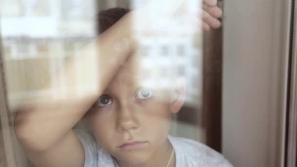 Грустный ребенок смотрит в окно — стоковое видео