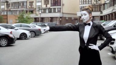 Siyah elbise ceket bir pandomim kız kamera için pozlar.