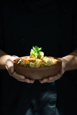 Elleri tabakta deniz ürünleri pilavı tutuyor.