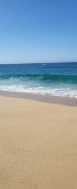 Deniz dalgaları ve mavi gökyüzü olan güzel sahil