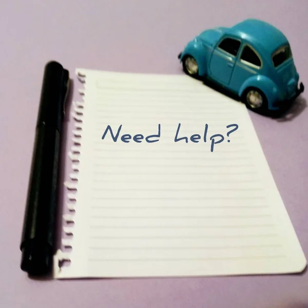 It says, need help? on a white sheet of paper. There\'s a pen and a toy car. A very attractive slogan for companies.