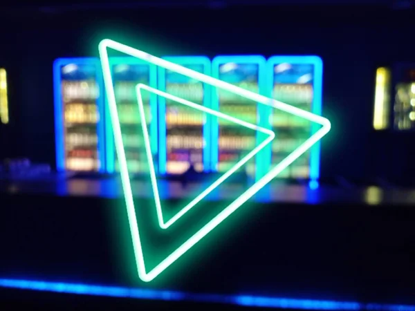 Green neon triangle shape is on the blue blurred bar photo. Dynamic and energetic.