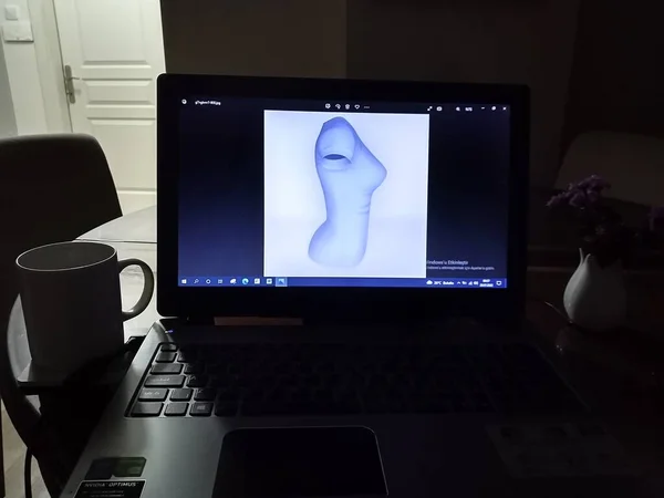 3D T-shirt model on computer screen. Home mode. A mug of coffe and laptop.