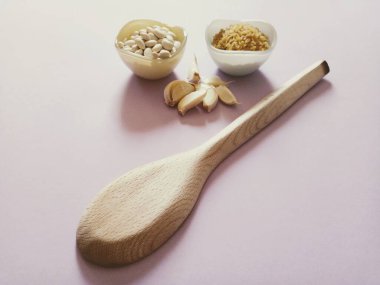 Haricot beans, coarse bulgur, garlics and wooden spoon on the lilac background. Legumes.