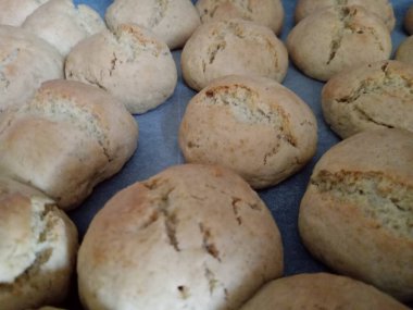 Cookies made with flour, sugar, vanilla, baking powder, egg and oil are on the tray. Close up.