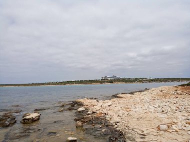 Deniz ve bulutlu hava. Ayrıca büyük bir otel var..