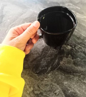 Kafede elinde kahve fincanı tutan spor elbiseli bir kadın..