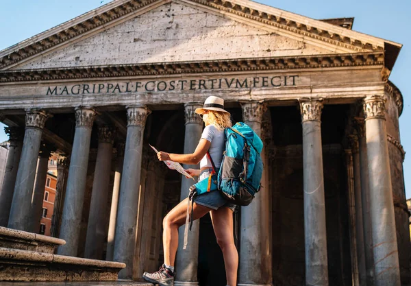 Young woman holds her map of Rome to discover the city and get to know it better, digital nomad