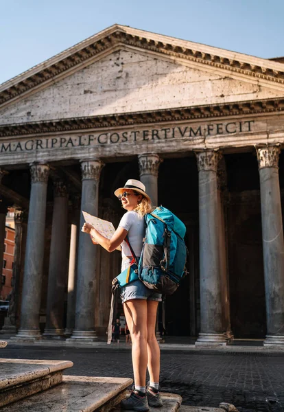 vertical shot of Young woman holds her map of Rome to discover the city and get to know it better, digital nomad