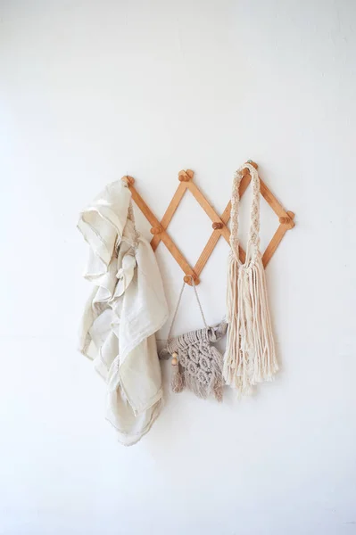 Décor objets accrochés sur un mur blanc sur un cintre en bois. Macramé, serviettes. Style rustique. — Photo
