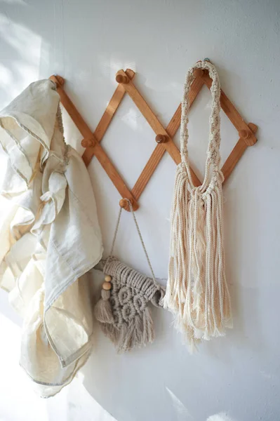 Décor objets accrochés sur un mur blanc sur un cintre en bois. Macramé, serviettes. Style rustique. — Photo