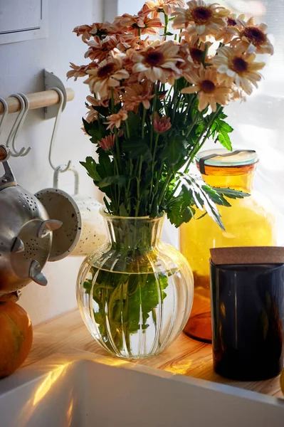 Um buquê de margaridas fica na cozinha perto da pia. luz de uma grande janela. Espaço rústico acolhedor. — Fotografia de Stock