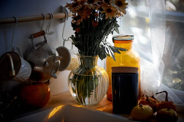 Egy csokor százszorszép áll a konyhában a mosogató mellett. fény egy nagy ablakból. Hangulatos rusztikus tér. — Stock Fotó