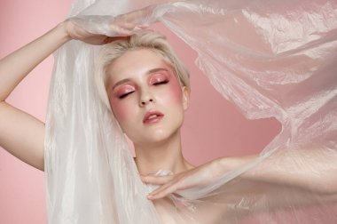 Yüzü sarı saçlı, doğal makyajlı, açık tenli bir kadın. Güzellik gözcüleri