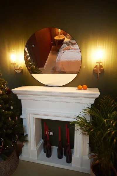 Cheminée blanche décorative avec bougies rouges et miroir rond. Décoration de chambre. — Photo