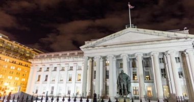 The north entrance of the U.S. Department of the Treasury Building and Albert Gallatin statue in downtown Washington, D.C. seen in a nighttime time-lapse that pans from left to right.