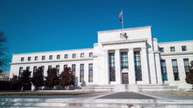 A daytime time-lapse of the Marriner S. Eccles Federal Reserve Board Building in Washington, D.C. on a sunny winter day. The camera pans from left to right.
