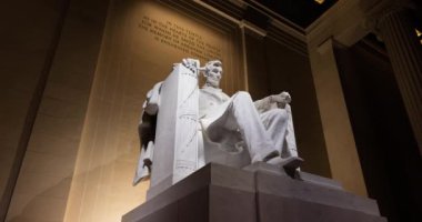 The Abraham Lincoln statue within the Lincoln Memorial in Washington, D.C. at night. The camera tracks left to right in this time-lapse video